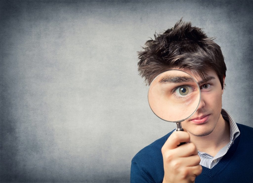 Man looking through a magnifying glass, 4 ways to handle denied loan application