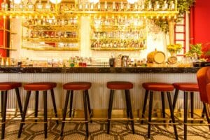 A stylish bar set up in a restaurant showcasing red stools and elegant gold accents to represent an article about restaurant business loan denial.