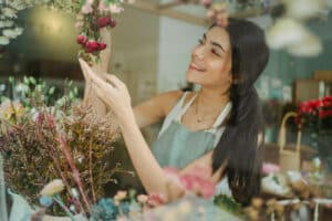 A female business owner arranging flowers at her flower shop seems happy because she has financing options for her business.