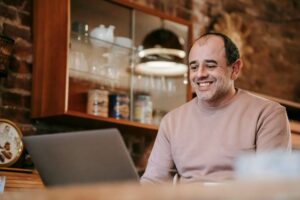 A business owner smiling at a table with a laptop representing the ease and satisfaction of instant approval for a business line of credit.