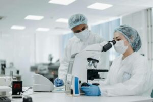 Two partners and doctors in a laboratory with coats analyzing a microscope represent the benefit of getting a medical practice loan for their business.