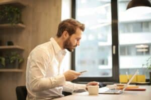 A picture of a man on a laptop reviewing his business credit report to describe an article about what business credit is, how to calculate it, and how to establish it.